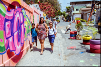 mulher com duas crianças caminha em calçada ando por muro com grafite