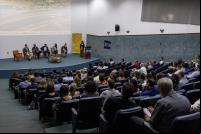 plateia em auditório olha para pessoa falando no palco