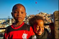 Dois pequenos moradores do Complexo do Alemão. A comunidade, antes com o a pé ou por transportes informais, conta agora com um teleférico que a conecta até terminais de transportes e serviços básicos, garantindo o a empregos e a saúde e educação a seus residentes. (Foto: Clément Jacquard/Flickr).