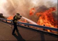 Bombeiro combate incêndio na Ronald Reagan Freeway, também conhecida como Highway 118, em Simi Valley, Califórnia (foto: Ringo H.W. Chiu / AP)