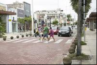 pessoas atravessam rua em faixa de segurança elevada