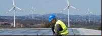 homem durante instalação de  solar com estações de energia eólica ao fundo