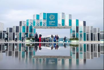pessoa caminha no pórtico de entrada da COP29 em Baku