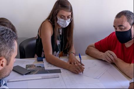 mulher desenha em projeto de rua enquanto pessoas no entorno observam