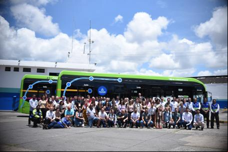 grupo de pessoas reunido em frente a ônibus elétrico