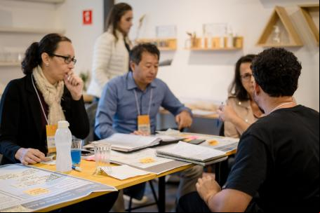 pessoas reunidas discutindo ideias em torno de um cartaz com os dizeres "plano de ação"