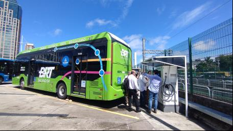 pessoas conversam ao lado de ônibus elétrico