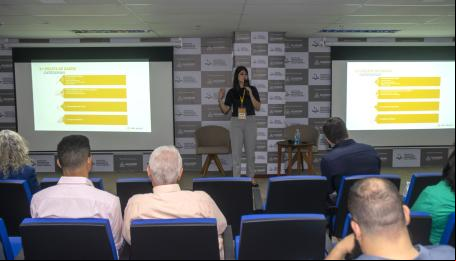 mulher fala em pé enquanto público assiste