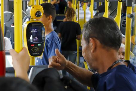 homem dentro de ônibus e catraca com escrito tarifa zero