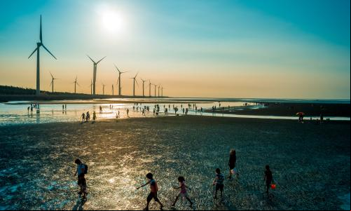 pessoas caminham próximas a usinas de energia eólica