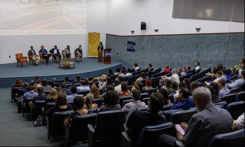 plateia em auditório olha para pessoa falando no palco
