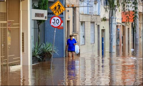 pessoa caminha em meio a enchente em porto alegre