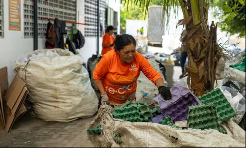 Uma mulher separa uma grande sacola de recicláveis de papelão.