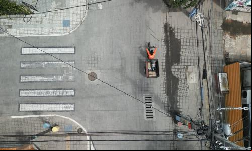 Vista aérea de um homem andando em um triciclo elétrico por uma rua da cidade.