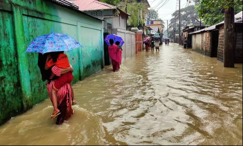 Pessoas percorrendo ruas inundadas em Sylhet, Bangladesh, em junho de 2024.