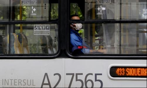 homem dentro de ônibus público com janela aberta e máscara
