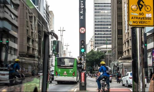 homem em bicicleta em ciclovia de são paulo aguarda semáforo em cruzamento da rua augusta